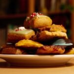 A close-up shot of colorful assorted cookies stacked on a white plate.