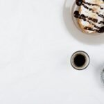 Top view of a breakfast setup with coffee, pastries, and cornflakes on white background.
