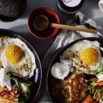 A delicious breakfast featuring fried eggs, fresh salad, and toast on a plate.