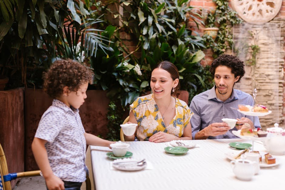 A family enjoys tea together in a beautiful indoor garden setting, surrounded by greenery.