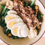 Delicious protein-packed bowl featuring tuna, boiled eggs, green beans, and hummus.