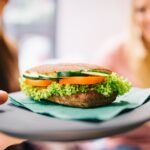 Healthy vegetarian sandwich with cucumbers and tomatoes served on a dark plate.